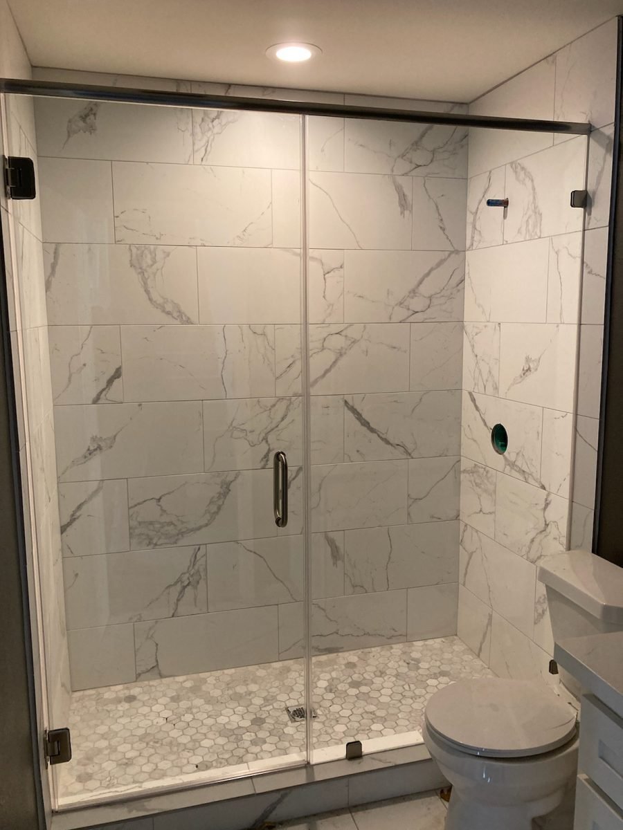 Tub-to-shower conversion with frameless door and inline panel, marble tile and hex mosaic floor, Houston TX
